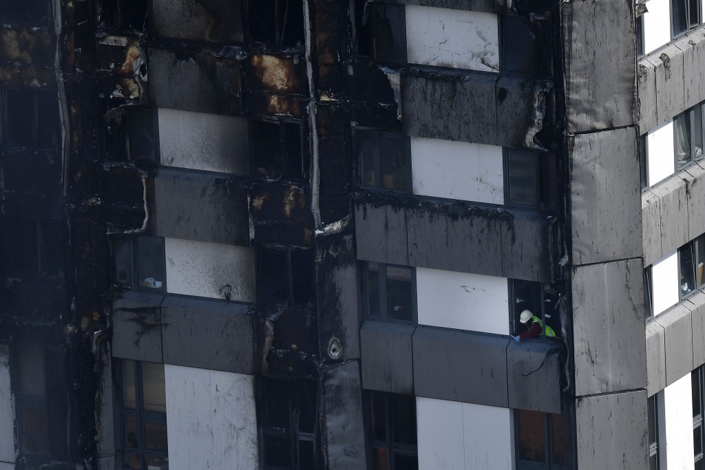 A fireman is seen at a window of the Grenfell Tower after a fire ripped through the building in west London on June 14, 2017. At least six people were killed Wednesday when a massive fire tore through a London apartment block overnight, with survivors voicing anger over longstanding safety fears at the 24-storey Grenfell Tower. / AFP PHOTO / Ben STANSALL