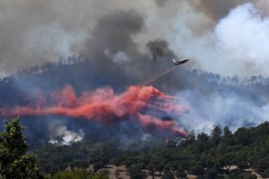 A fire fighting Canadair aircraft drops fire retardant over a fire near Bormes-les-Mimosas, southeastern France, on July 26, 2017. At least 10,000 people, including thousands of holidaymakers, were evacuated overnight after a new wildfire broke out in southern France, which was already battling massive blazes, authorities said on July 26. / AFP PHOTO / Anne-Christine POUJOULAT