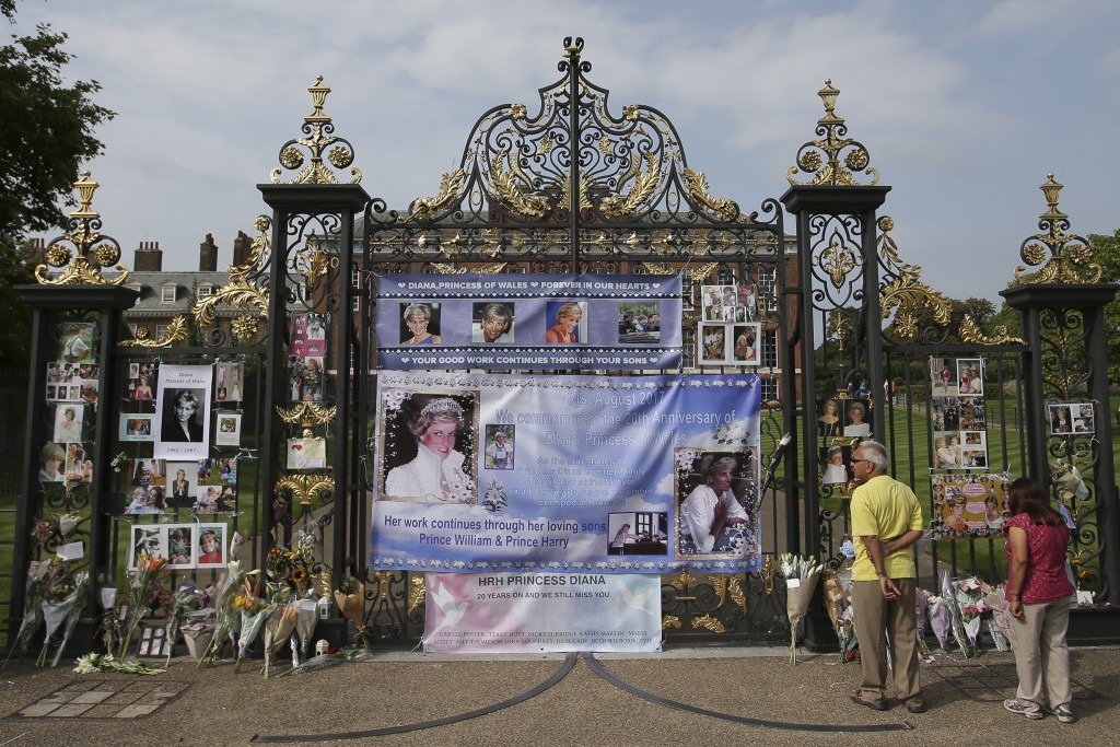 Visitors look at photographs of Diana, Princess of Wales, and floral tributes left outside Kensington Palace in Central London on August 29, 2017 ahead of the 20th anniversary of Princess Diana's death. Britain prepares to mark the twentieth anniversary of the death of Diana, Princess of Wales. August 31, 1997, Britain's Diana, Princess of Wales, died in a high-speed car crash in Paris. For the week following, leading up to her spectacular funeral, Britain was plunged into an unprecedented outpouring of popular grief which shook the monarchy.  / AFP PHOTO / Daniel LEAL-OLIVAS