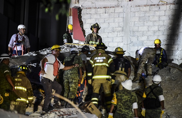 Rescuers, firefighters, policemen, soldiers and volunteers remove rubble and debris from a flattened building in search of survivors after a powerful quake in Mexico City on September 19, 2017. The death toll from a powerful earthquake that rocked Mexico on September 19 has surged to 248 people, the head of the national disaster response agency, Luis Felipe Puente, said on Twitter. / AFP PHOTO / RONALDO SCHEMIDT