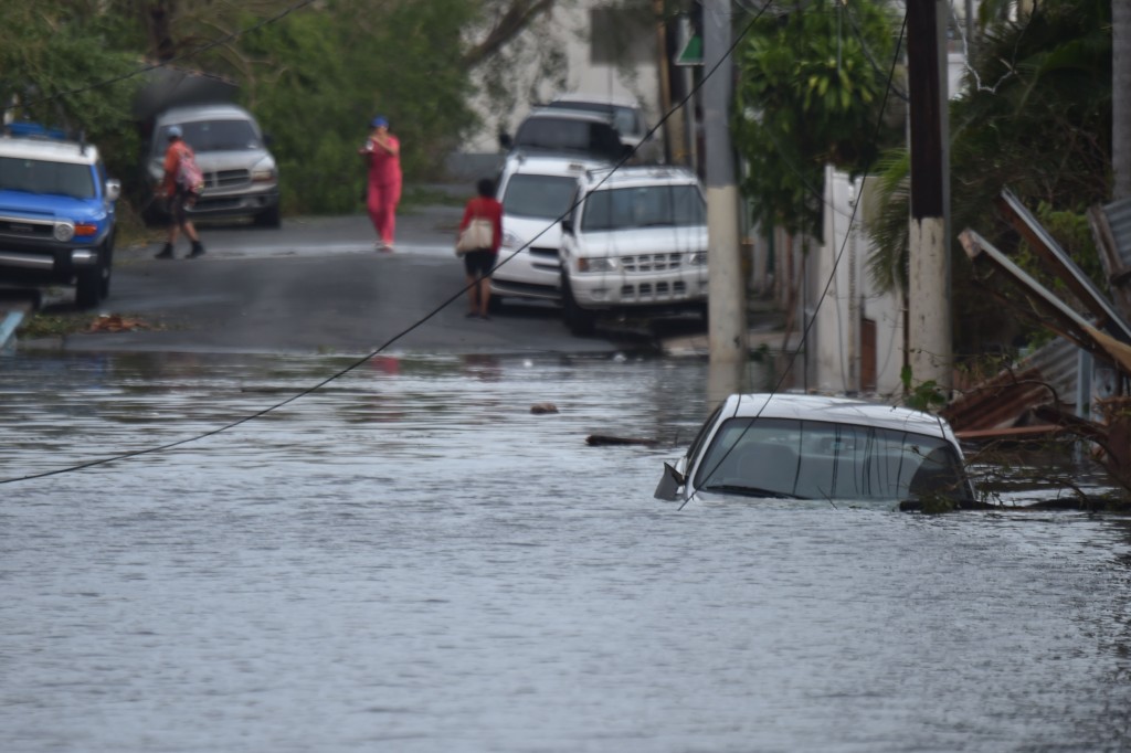 A car is viewed stuck in a flooded street in Santurce, in San Juan, Puerto Rico, on September 21, 2017.  Puerto Rico braced for potentially calamitous flash flooding on Thursday after being pummeled by Hurricane Maria which devastated the island and knocked out the entire electricity grid. The hurricane, which Puerto Rico Governor Ricardo Rossello called "the most devastating storm in a century," had battered the island of 3.4 million people after roaring ashore early Wednesday with deadly winds and heavy rain.  / AFP PHOTO / HECTOR RETAMAL