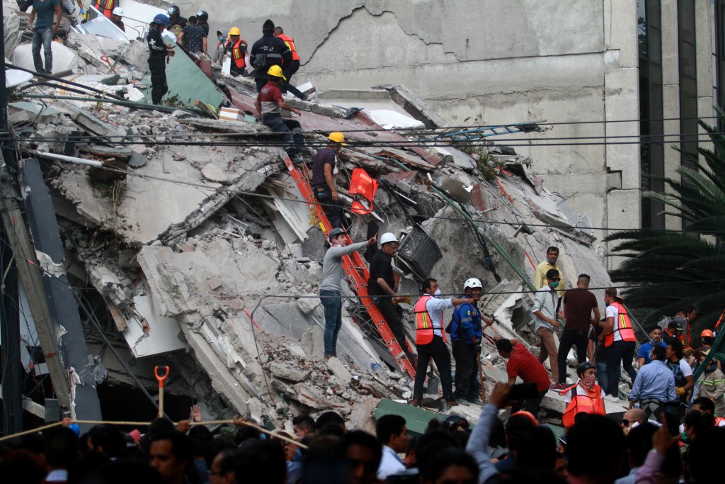 Rescuers and volunteers remove rubble and debris from a flattened building in search of survivors after a powerful quake in Mexico City on September 19, 2017. A powerful earthquake shook Mexico City on Tuesday, causing panic among the megalopolis' 20 million inhabitants on the 32nd anniversary of a devastating 1985 quake. The US Geological Survey put the quake's magnitude at 7.1 while Mexico's Seismological Institute said it measured 6.8 on its scale. The institute said the quake's epicenter was seven kilometers west of Chiautla de Tapia, in the neighboring state of Puebla. / AFP PHOTO / VICTOR CRUZ