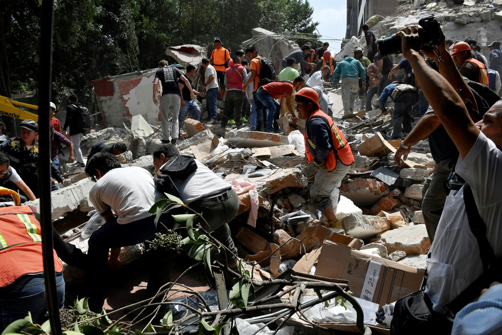 People remove debris of a building which collapsed after a quake rattled Mexico City on September 19, 2017. A powerful earthquake shook Mexico City on Tuesday, causing panic among the megalopolis' 20 million inhabitants on the 32nd anniversary of a devastating 1985 quake. The US Geological Survey put the quake's magnitude at 7.1 while Mexico's Seismological Institute said it measured 6.8 on its scale. The institute said the quake's epicenter was seven kilometers west of Chiautla de Tapia, in the neighboring state of Puebla. / AFP PHOTO / Omar TORRES