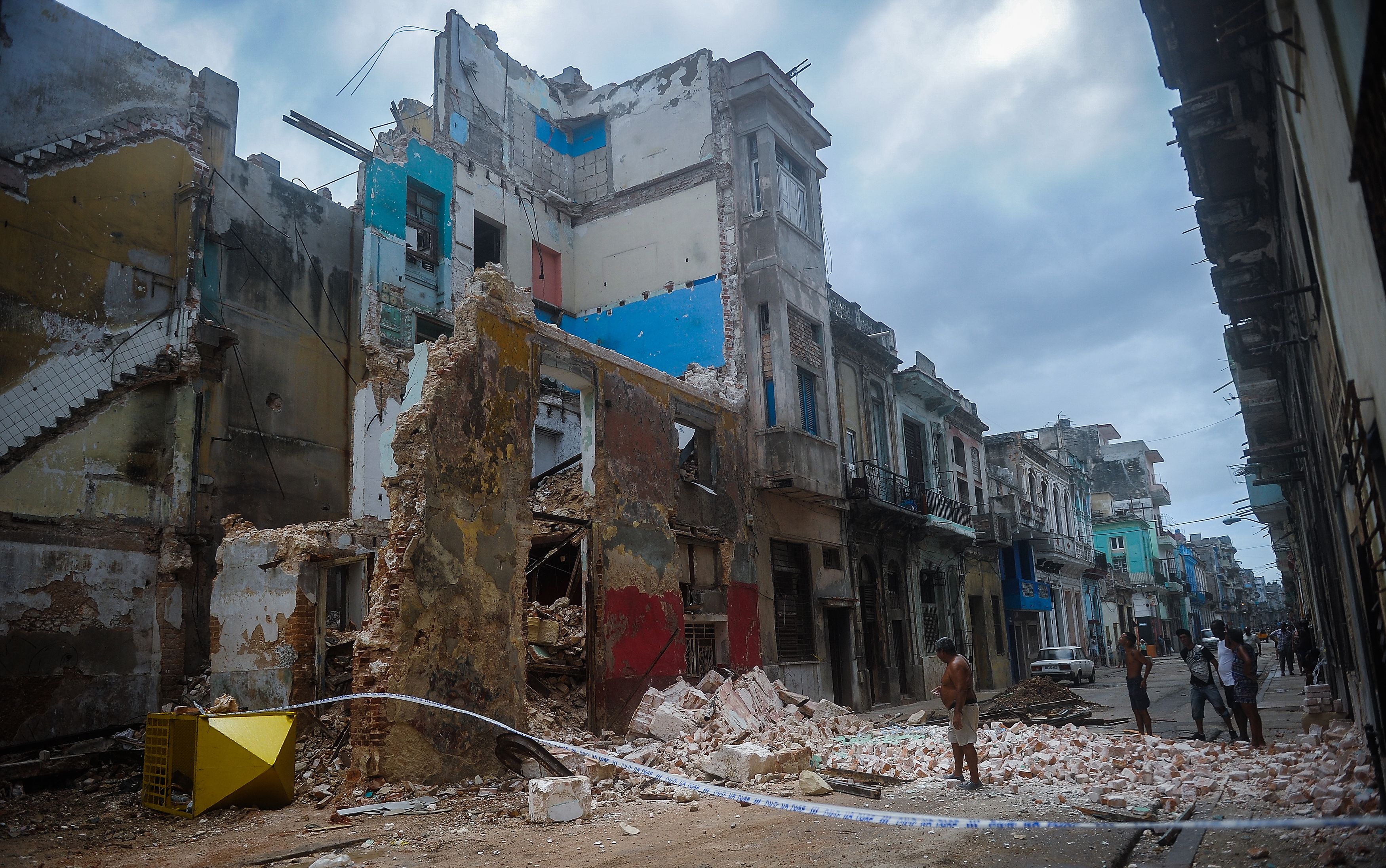 TOPSHOT - Cubans stand bt a collapsed building in Havana, on September 9, 2017.  Irma's blast through the Cuban coastline weakened the storm to a Category Three, but it is still packing 125 mile-an-hour winds (205 kilometer per hour) and was expected to regain power before hitting the Florida Keys early Sunday, US forecasters said. The Cuban government extended its maximum state of alert to three additional provinces, including Havana, amid fears of flooding in low-lying areas. / AFP / YAMIL LAGE
