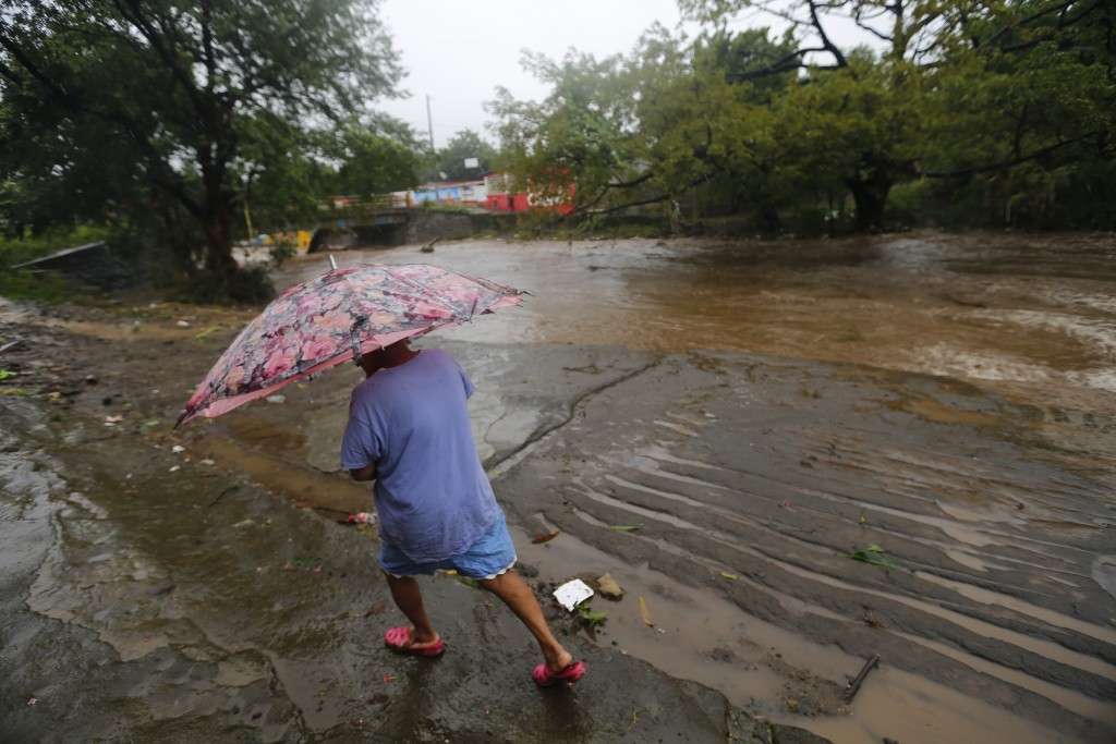 A woman walks in the rain near the flooded Masachapa River following the passage of Tropical Storm Nate in the city of Masachapa, about 60km from the city of Managua on October 5, 2017. A tropical storm sliding north along Central America Thursday has unleashed heavy rains killing at least nine people in Costa Rica and Nicaragua, with forecasters predicting it could strengthen into a hurricane headed for the United States. / AFP PHOTO / INTI OCON
