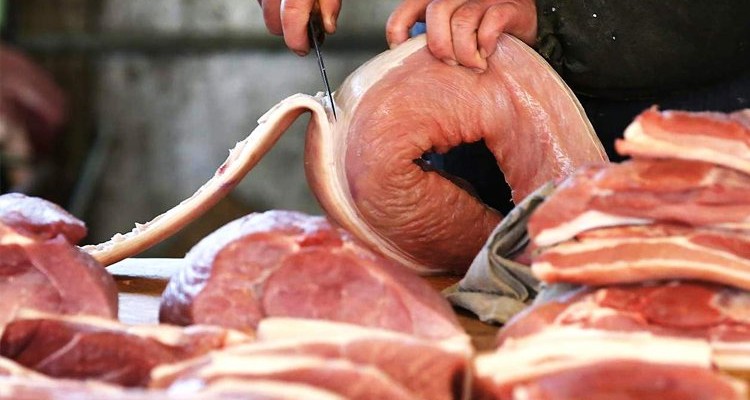 cocinero cortando carne de cerdo cruda