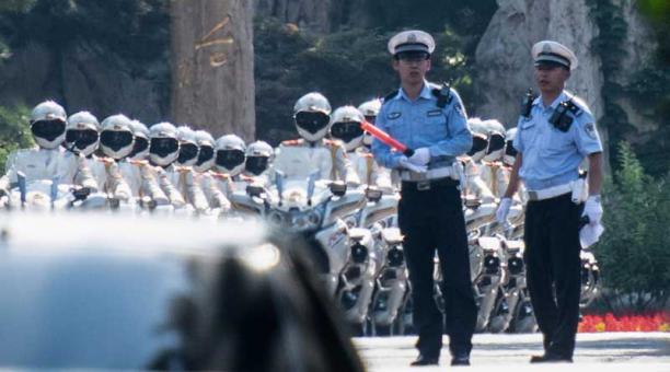 Los ciclistas chinos hacen honor a los guardias que se preparan para escoltar el automóvil que se cree lleva el líder norcoreano Kim Jong Un en la casa de huéspedes del estado de Diaoyutai en Beijing el 19 de junio de 2018