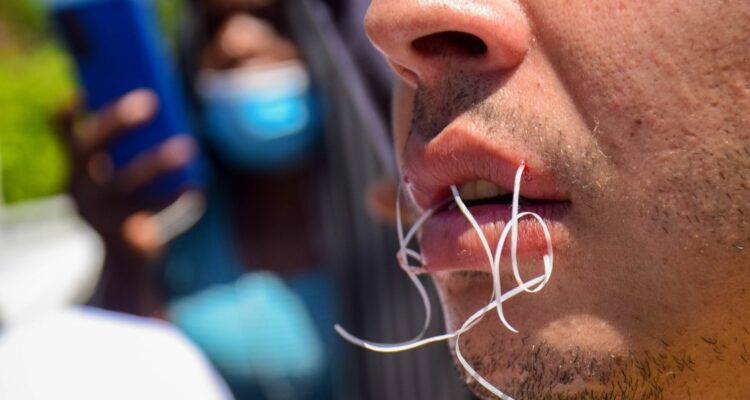 Migrantes se cosen los labios